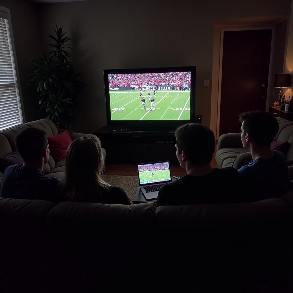 A group of friends gathered around a laptop, enjoying a Butte High School football live stream.