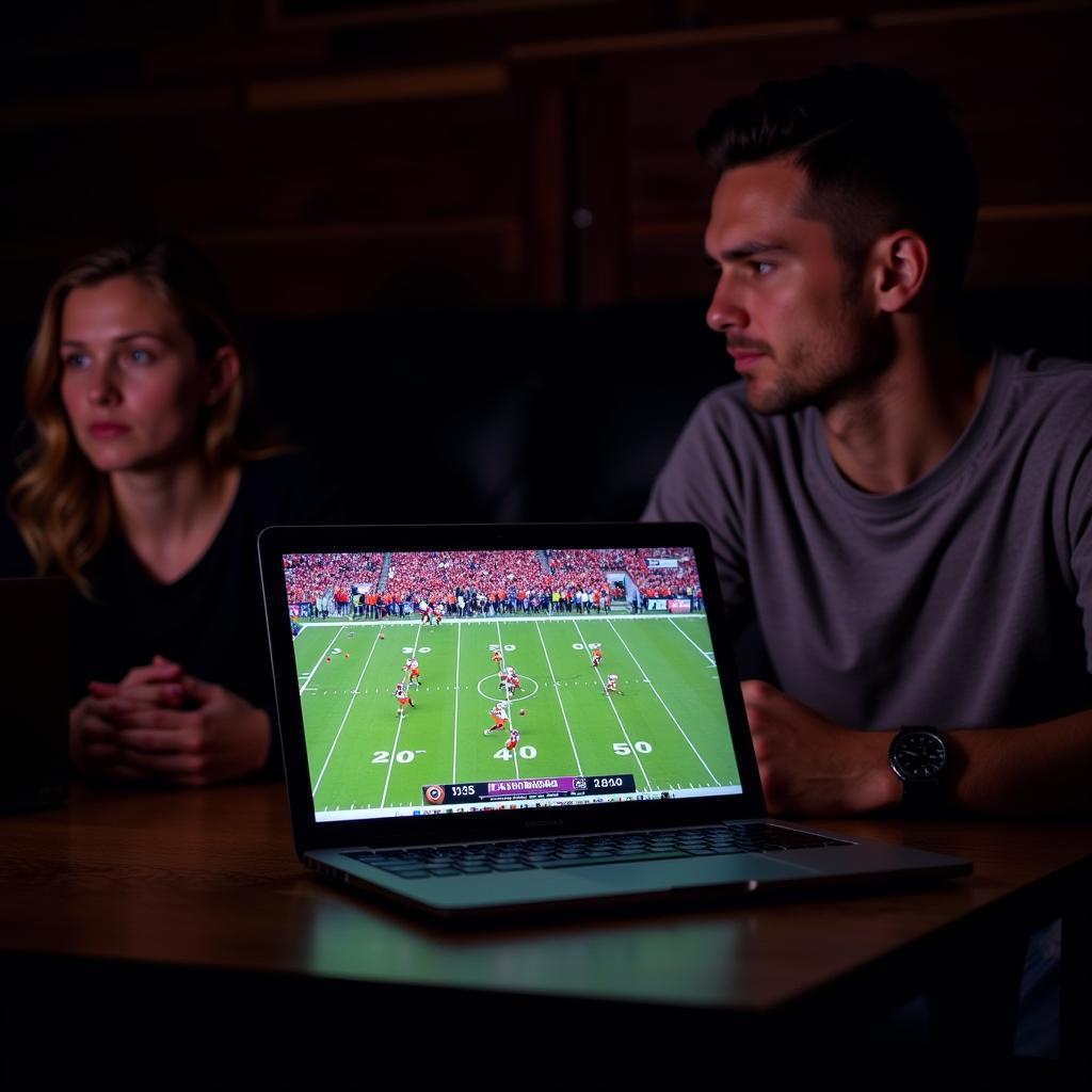 Laptop showing Clemson vs South Carolina live stream with fans watching